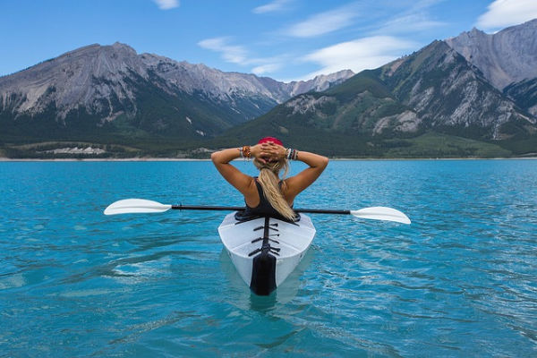 girl kayaking on a lake surrounded by mountains