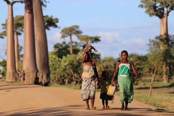 three african girls walking on a dirt road 