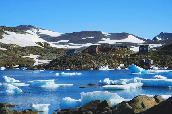 Red house against bright blue icy water in Greenlands arctic circle 
