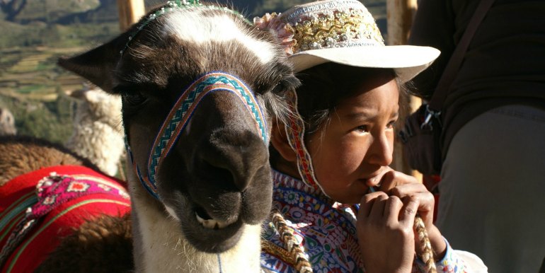 Young girl and llama in traditional dress in Peru