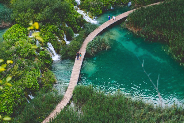 a blue lake with people walking on a bridge in Croatia