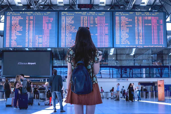 Young woman looking at list of international departures in the airport