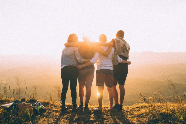 four friends wrapping their arms around each other outdoors