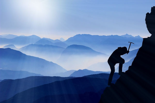 Traveler climbing a mountain with pickaxe