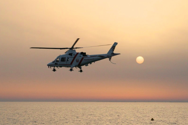 Helicopter flying over the ocean at sunset