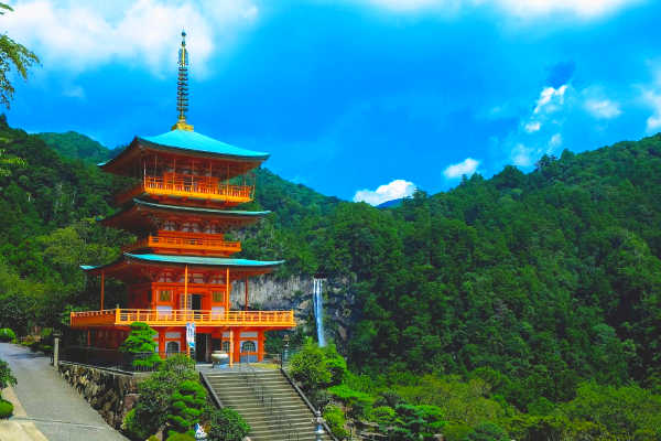 Orange Japanese temple against green forest backdrop