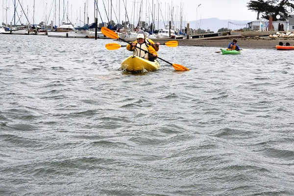 people in a yellow kayak paddling near the shore