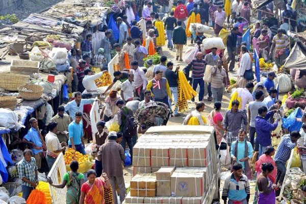 A chaotic street in India filled with people and a large truck at the market