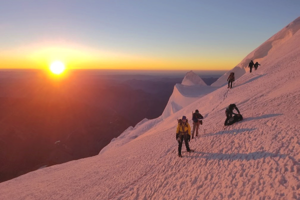 People walking on a snow covered mountain during sunset hour