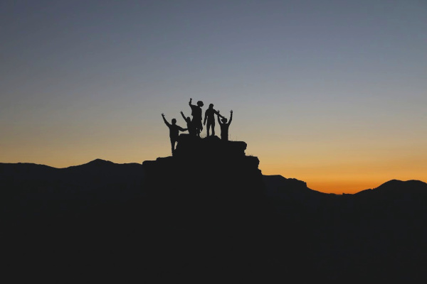 Sihlouette of friends on top of a mountain at sunset