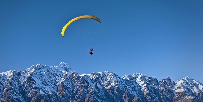 Solo skydiver over jagged snow covered mountains