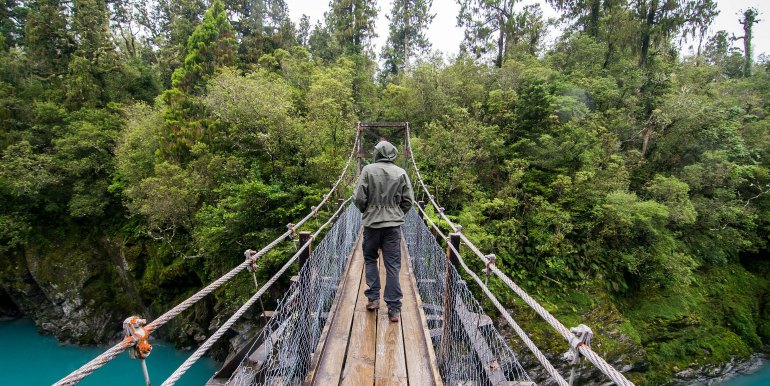 Traveler on hanging bridge over river in New Zealand