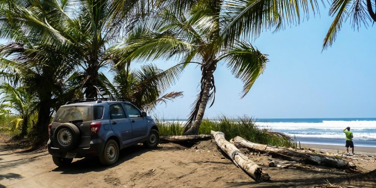 Car parked beside beach and palm trees in Costa Rica