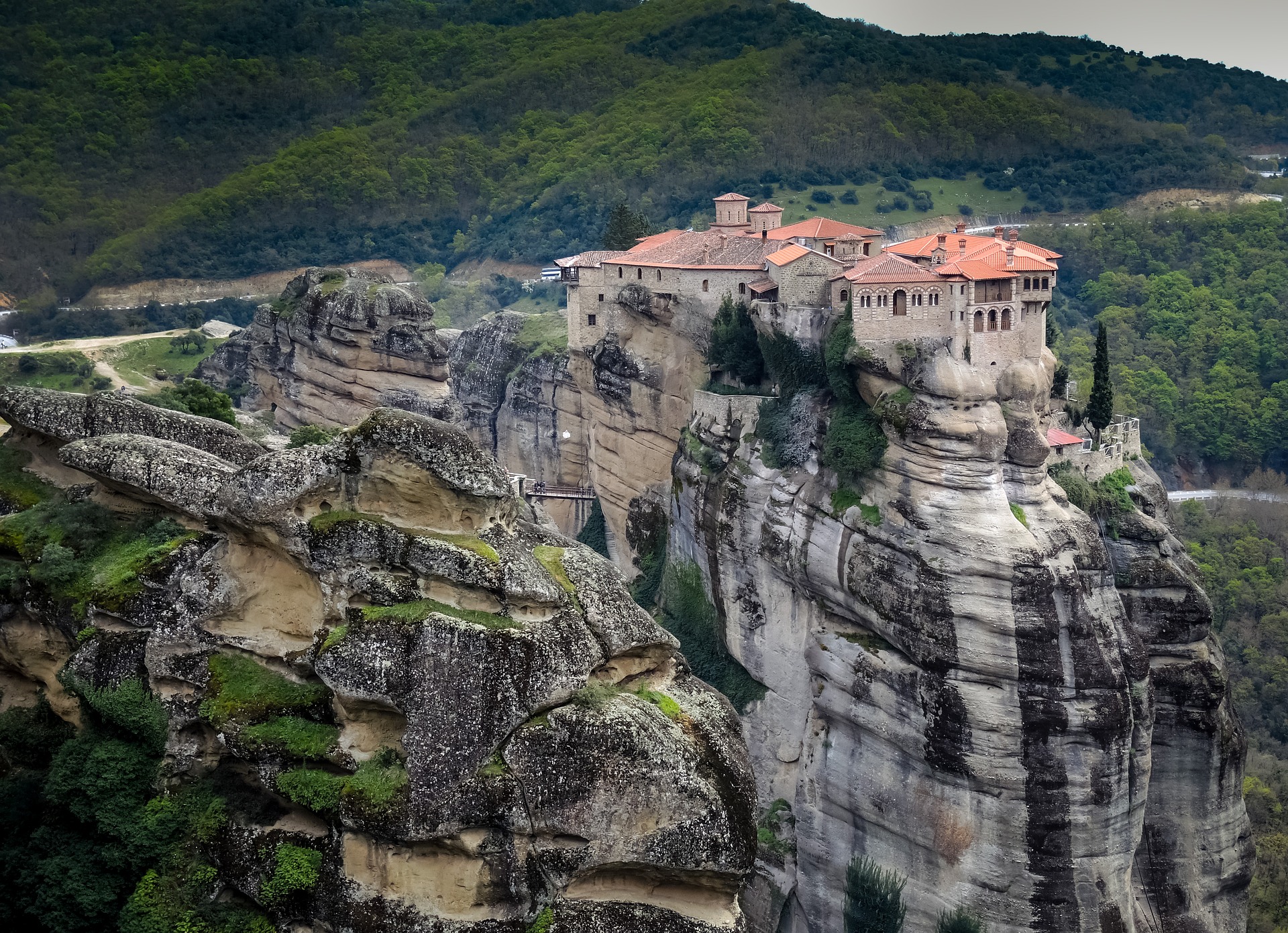 Ancient buildings that have orange roofs sit on top of huge rock formations