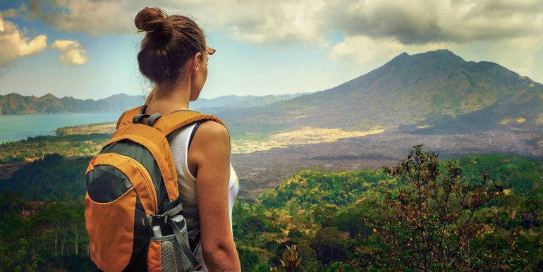 Young female hiker with backpack looking at volcano