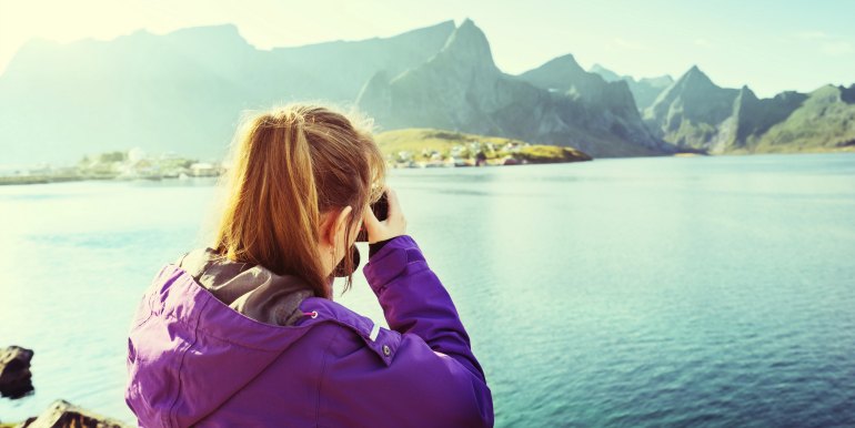Young female traveler taking pictures of mountains